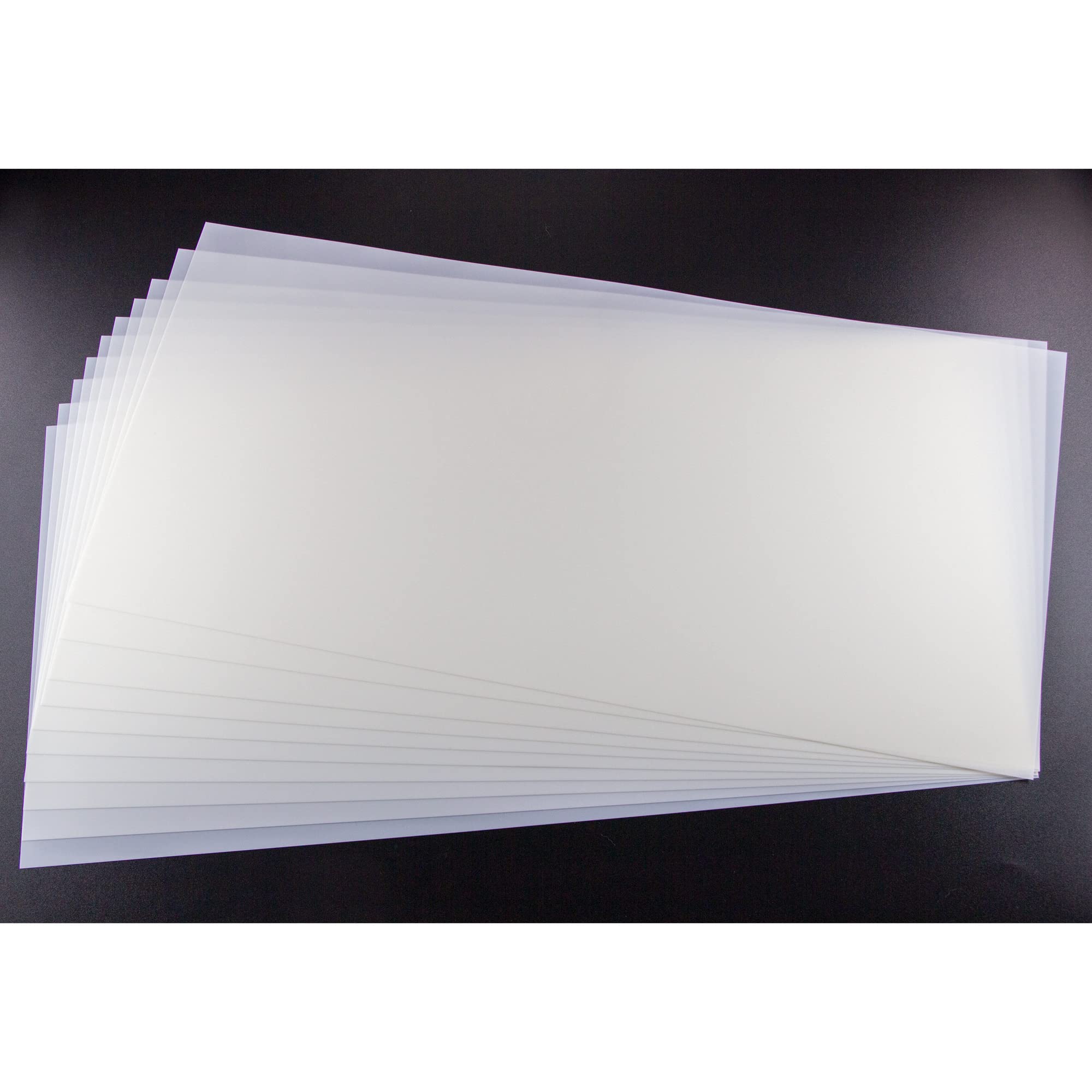 A stack of blank translucent mylar stencil sheets fanned out, showing the clear polyester film material