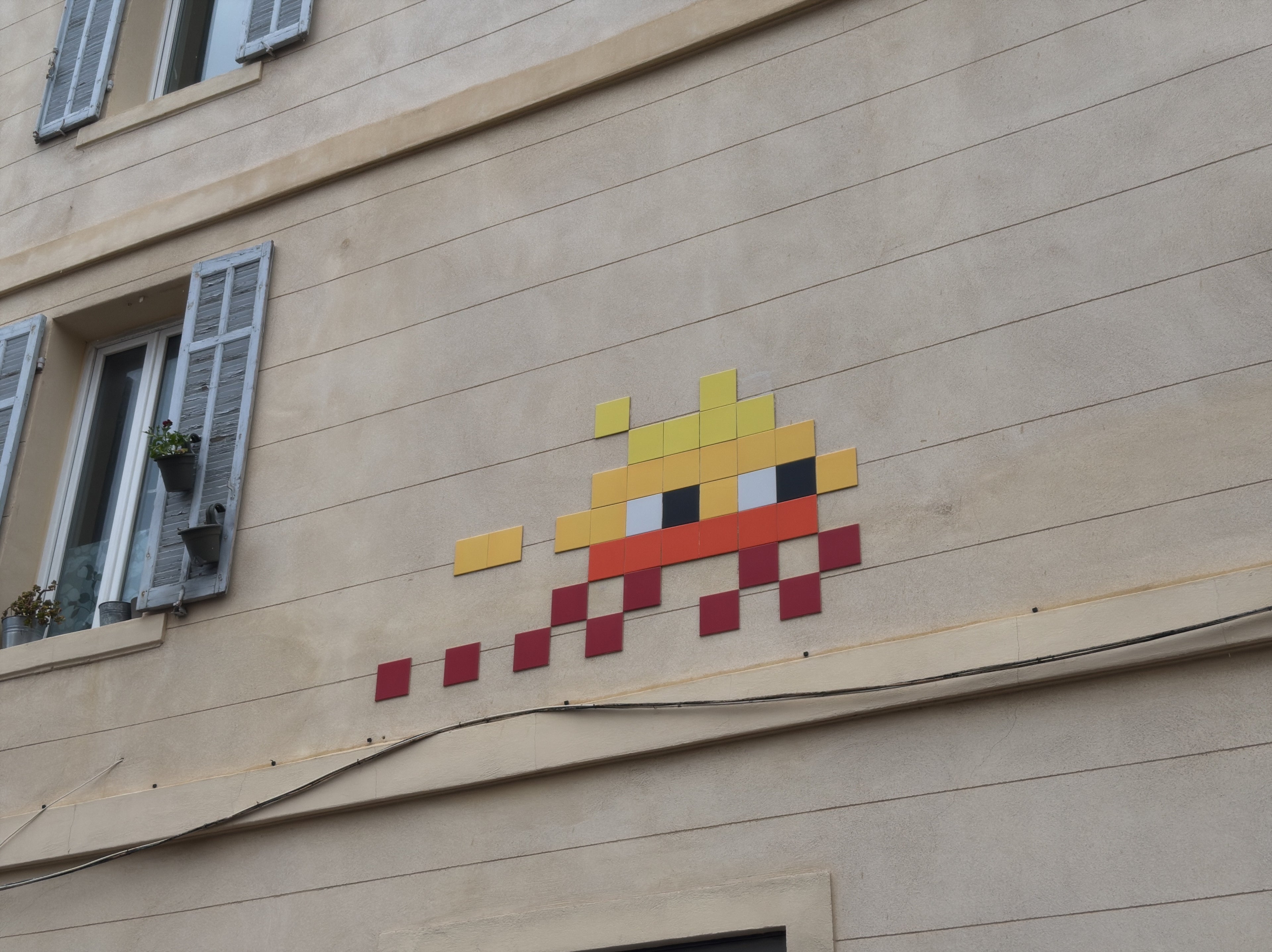 Invader ceramic tile mosaic of a Space Invader alien on a wall in the Le Panier neighbourhood of Marseille, 2026