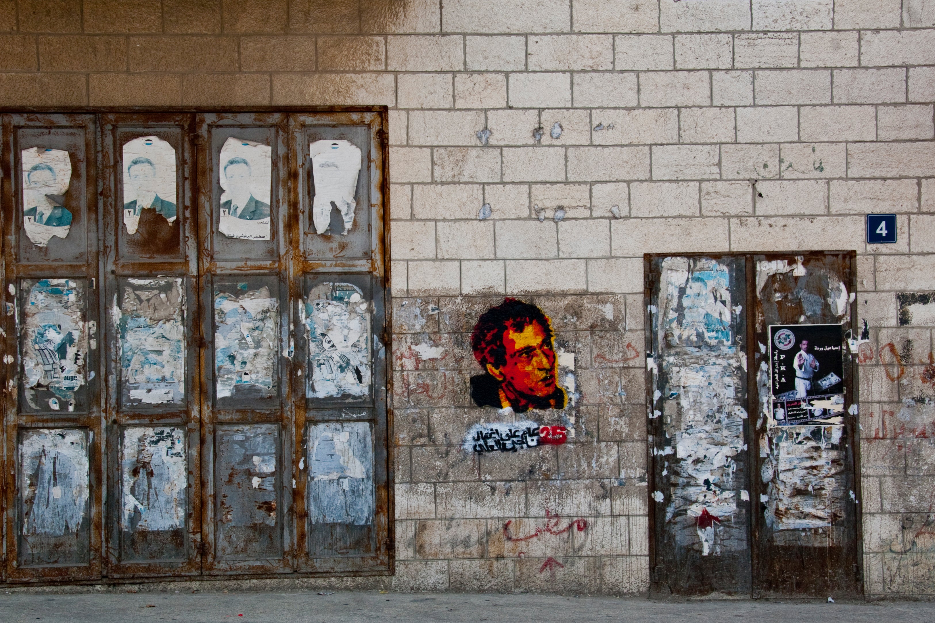 4-color stencil graffiti portrait of Naji al-Ali on a wall in Ramallah, 2012, showing multi-layer color stencil technique