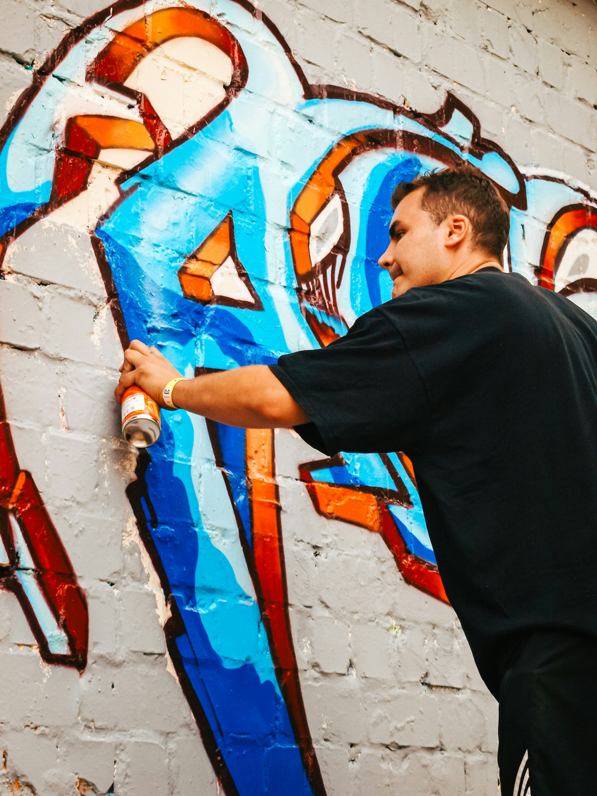 A man actively spray painting graffiti on a wall at Berlin Graffiti Box Jam 2009